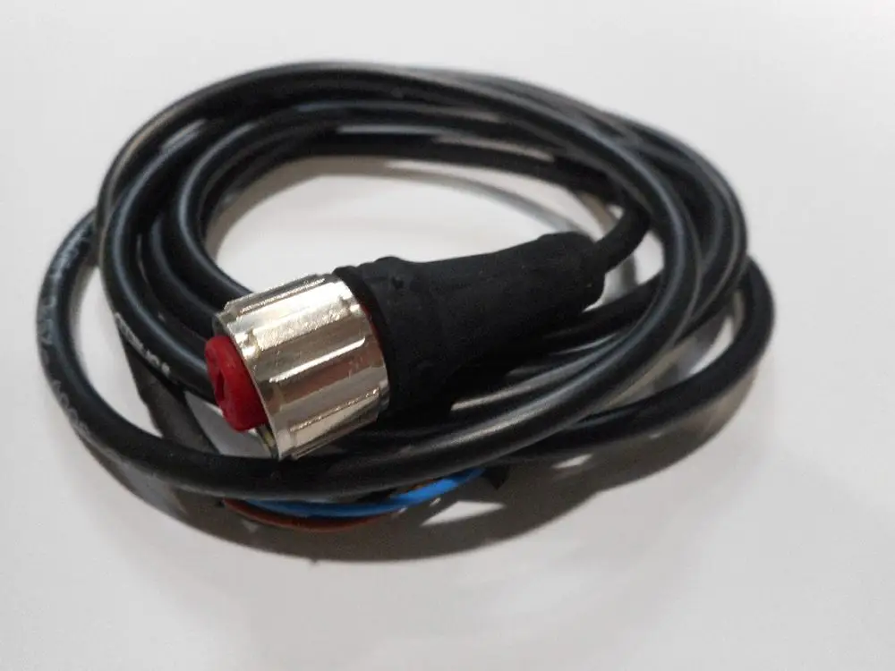 Schwarzes Kabel mit einer angeschlossenen Metallkupplung und rotem Kunststoffelement, möglicherweise für einen Durchflusssensor von Remeha.